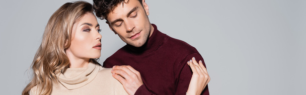 casual young couple in turtleneck jumpers embracing isolated on grey, banner - Photo, Image