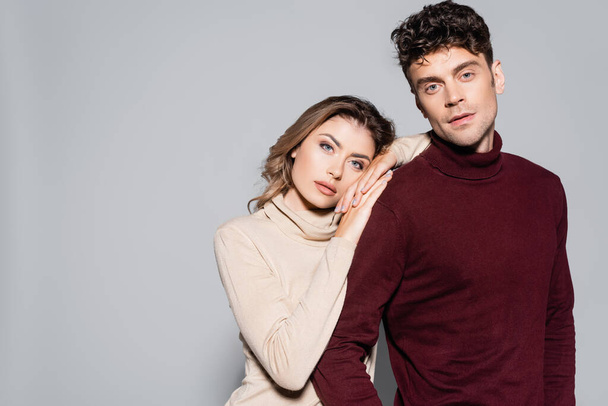 casual young couple in turtleneck jumpers embracing isolated on grey - Foto, immagini