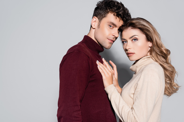side view of casual young couple in turtleneck jumpers isolated on grey - Zdjęcie, obraz