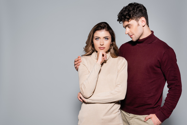 casual young couple in jumpers posing isolated on grey - Photo, Image