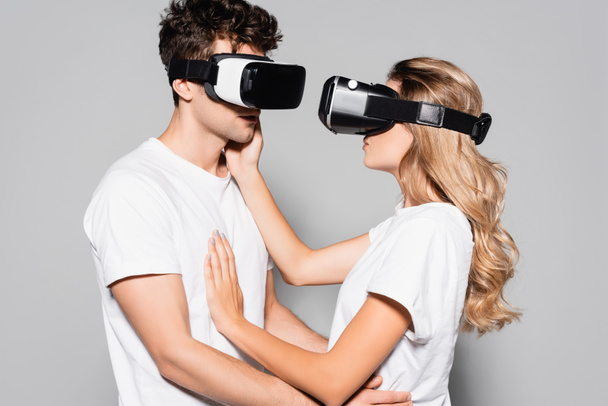 casual young couple in white t-shirts and vr headsets isolated on grey - Photo, image