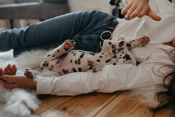 Junge Frau liegt auf dem Boden und spielt mit Welpe von Dalmatiner-Hund. - Foto, Bild