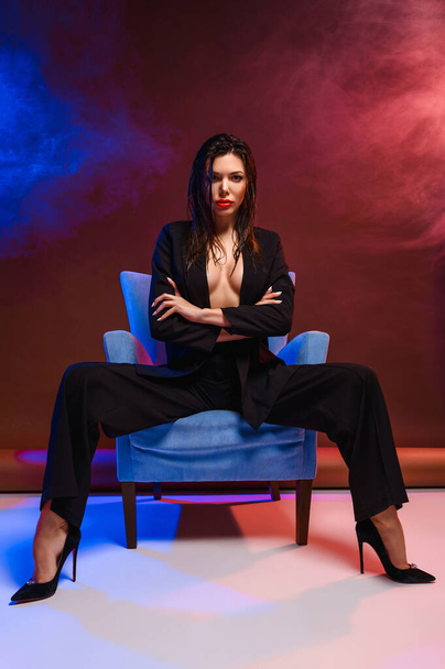 Attractive business woman in a business suit on an armchair - Fotoğraf, Görsel