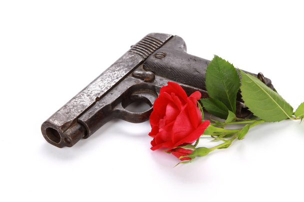 A closeup shot of a gun and a red rose isolated on a white background - Фото, изображение