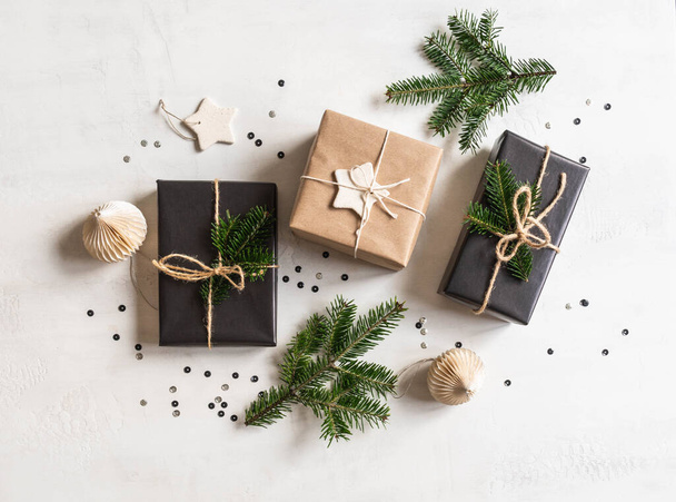 Vlakke lay-out van kerstcadeaus duurzaam verpakt. Kerstverpakking in natuurlijke en zwarte kleuren op een witte textuur achtergrond. Bovenaanzicht. - Foto, afbeelding