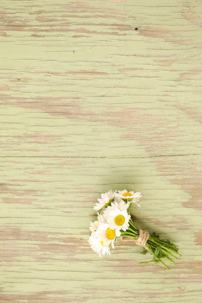 A closeup shot of a bunch of daisy flowers on a wooden surface - Fotografie, Obrázek
