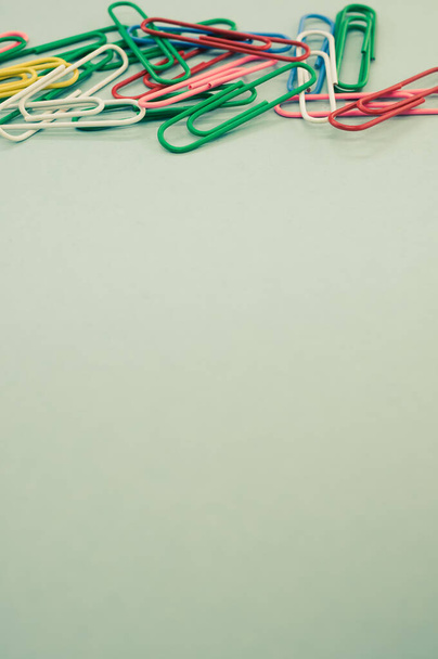 A vertical shot of multicolored paper clips on a piece of paper - Foto, Imagem