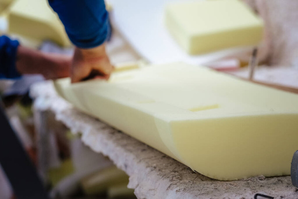 A vertical shot of a furniture maker shaping an upholstery foam - Foto, Imagen
