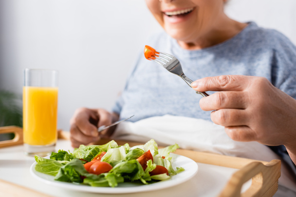 cropped view of joyful woman having breakfast in hospital, blurred background - Photo, image