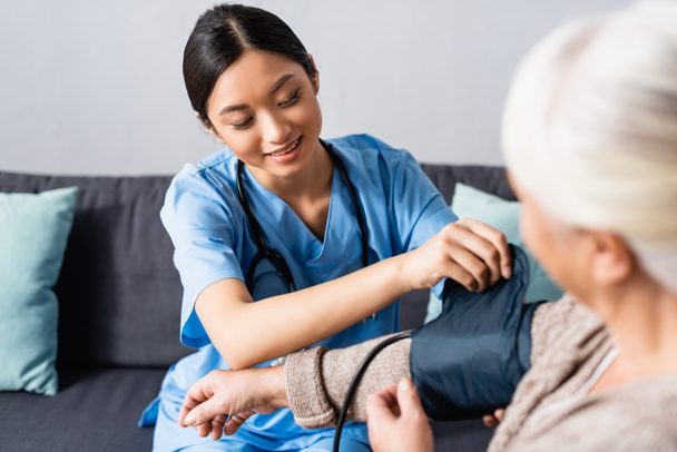jeune asiatique infirmière fixation manchette de tonomètre sur bras de femme âgée à l'hôpital - Photo, image