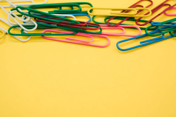 A closeup shot of multicolored paper clips on a piece of paper - Фото, изображение
