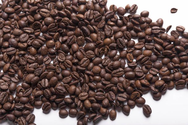 roasted coffee beans of various shades of brown scattered on a white surface. Coffee background or texture concept. - Foto, imagen