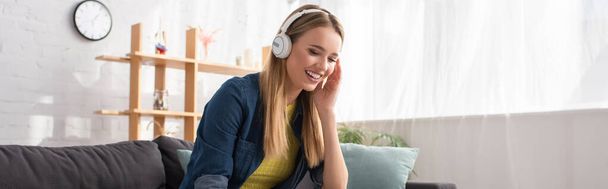 Happy blonde woman in headphones laughing at home on blurred background, banner - Valokuva, kuva