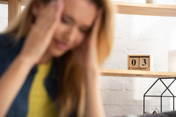 Wooden calendar on shelf with blurred tense woman on foreground - Foto, afbeelding