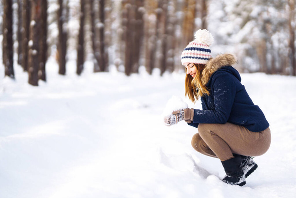 Happy winter time. Cute woman playing with snow  in snowy forest. Young lady in winter clothes enjoying the winter. Winter holiday. - Foto, imagen