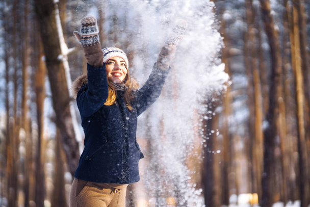 Happy winter time. Cute woman playing with snow  in snowy forest. Young lady in winter clothes enjoying the winter. Winter holiday. - Photo, Image