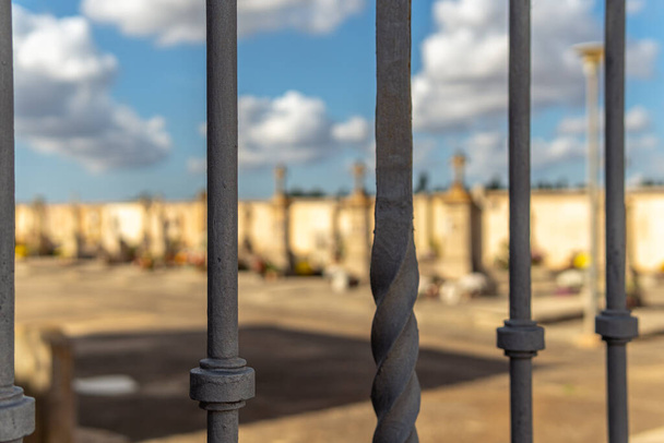 Kovový plot ohraničující hřbitov. V pozadí rozostřené hrobky s efektem bokeh. Ostrov Mallorca, Španělsko - Fotografie, Obrázek