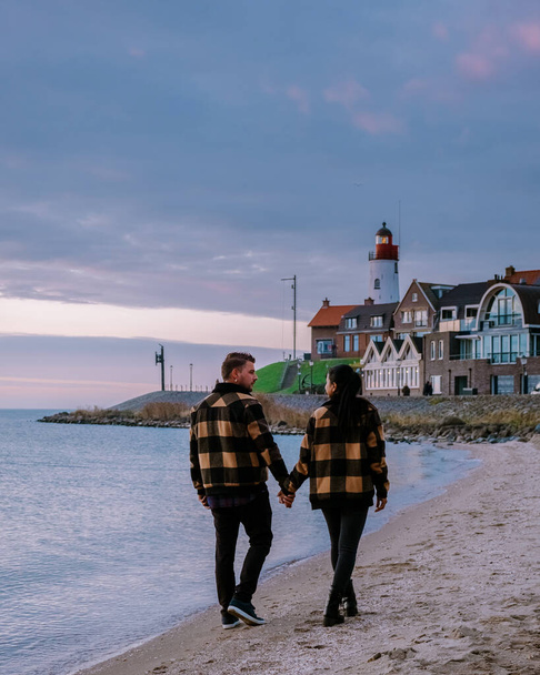 ウルク・フレヴォランド・オランダ、ウルク・オランダの小さな漁村港で夕日を見ているカップルの男性と女性 - 写真・画像