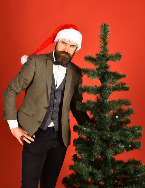 Man in classic suit and Santa hat on red background. - Fotografie, Obrázek