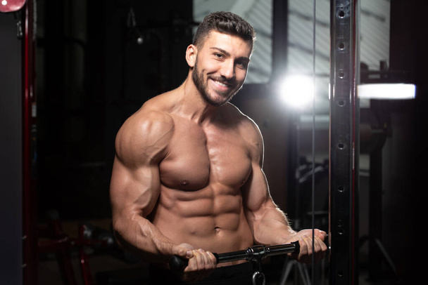 Muscular Fitness Bodybuilder Wykonywanie ciężkich ćwiczeń na bicepsy na maszynie z kablem w siłowni - Zdjęcie, obraz