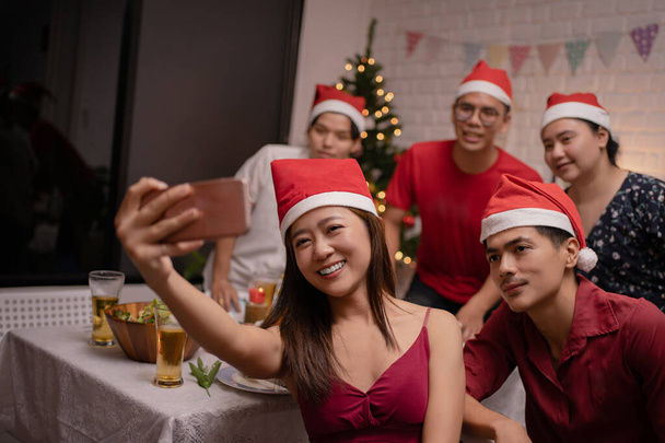 Bir grup Asyalı evdeki bir Noel partisinde yemek yerken selfie çekiyorlardı.. - Fotoğraf, Görsel