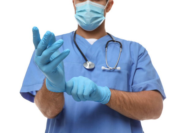 Doctor in protective mask putting on medical gloves against white background, closeup - Foto, Imagem