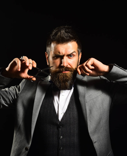Macho in formal suit holds and cuts beard and moustache - Foto, Bild
