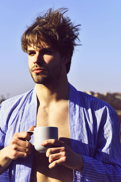 Caucasian macho in blue striped pajamas holding cup - Zdjęcie, obraz