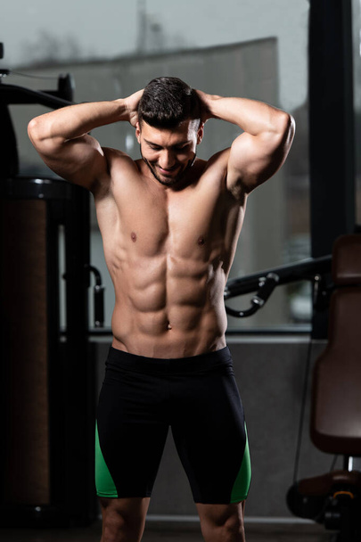 Ritratto di un giovane uomo in forma fisica che mostra il suo corpo ben addestrato - Modello di fitness culturista atletico muscolare in posa dopo gli esercizi - Foto, immagini
