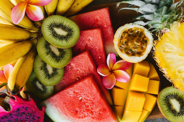 Tropical fruits assortment on a wooden plate. Stone background. - Foto, Bild