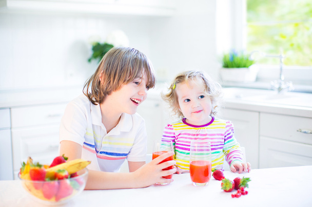 Garçon et sœur ayant des fruits et des céréales à la fraise pour le petit déjeuner
 - Photo, image