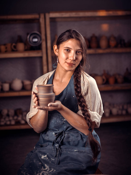 Charmante femme céramiste montre comment travailler avec l'argile et la roue de poterie. Concept d'art céramique. - Photo, image