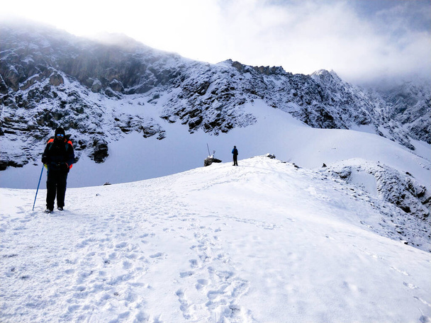 Wan, India - 2 giugno 2018: Escursionista ben attrezzato che cammina su un'enorme coltre di neve per raggiungere la cima della montagna indiana dell'Himalaya. - Foto, immagini