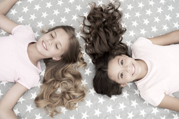 Girls with long curly hair lay on bed top view. Children perfect curly hairstyle looks cute. Conditioner mask organic oil keep hair shiny and healthy. Amazing curls tips. Make it curly but natural - Fotoğraf, Görsel