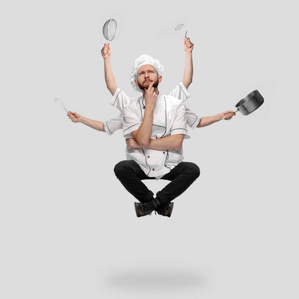 Cooker in uniform multitask like shiva isolated on gray studio background - Φωτογραφία, εικόνα