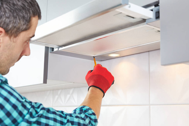 Man repairs range hood in the kitchen. Replacement filter in a cooker hood. - Foto, Imagem