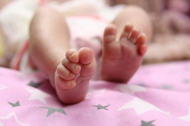 Tender sensitive baby feet on the bedspread - Photo, Image