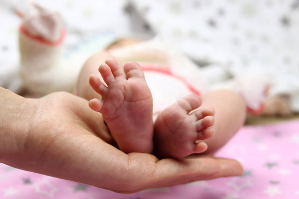 Τα πόδια του μωρού στο χέρι της μητέρας, η έννοια της αγάπης στην οικογένεια - Φωτογραφία, εικόνα