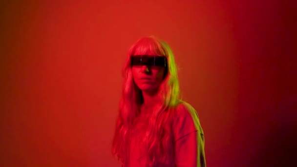 ξανθιά νεαρή λευκή γυναίκα που φοράει έξυπνα γυαλιά, γυαλιά επιστημονικής φαντασίας σε κόκκινο φόντο - Πλάνα, βίντεο