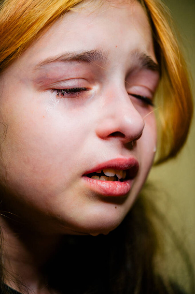 Μικρό λυπημένο κορίτσι μετά το κλάμα. Κλαίει το μικρό όμορφο κορίτσι με τα θλιμμένα πράσινα μάτια και κατσουφιασμένο πρόσωπο. Έφηβος με βαμμένες αφέλειες σε θλιβερή διάθεση - Φωτογραφία, εικόνα