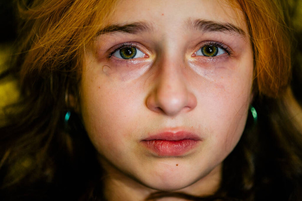 Mała smutna dziewczynka po płaczu. Płacząca mała piękna dziewczyna ze smutnymi zielonymi oczami i zmarszczoną twarzą. Nastolatek z farbowaną grzywką w smutnym nastroju - Zdjęcie, obraz