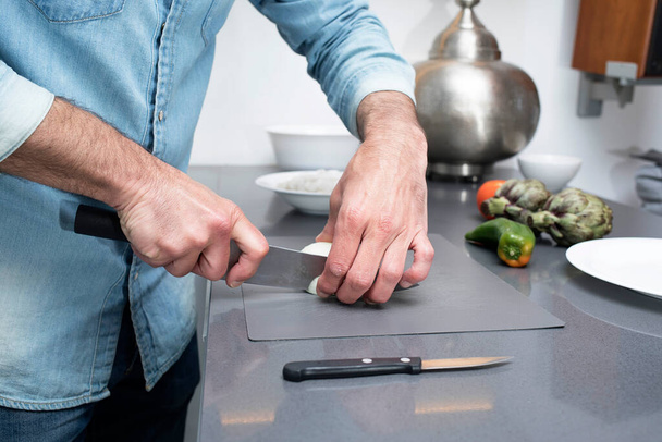 Cropped view of male cutting vegetables on chopping board in kitchen - Foto, Bild