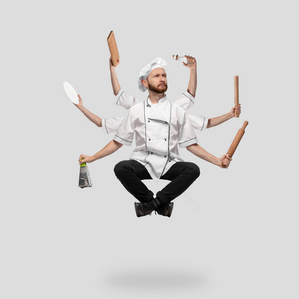 Cooker, chef, baker in uniform multitask like shiva isolated on gray studio background - Фото, изображение
