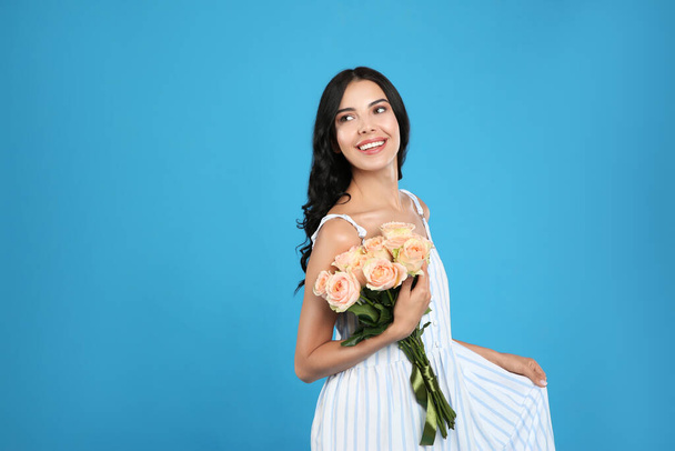 Portrait of smiling woman with beautiful bouquet on light blue background. Space for text - Фото, зображення