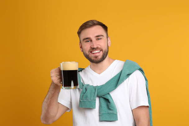 Handsome man with cold kvass on yellow background. Traditional Russian summer drink - Fotografie, Obrázek
