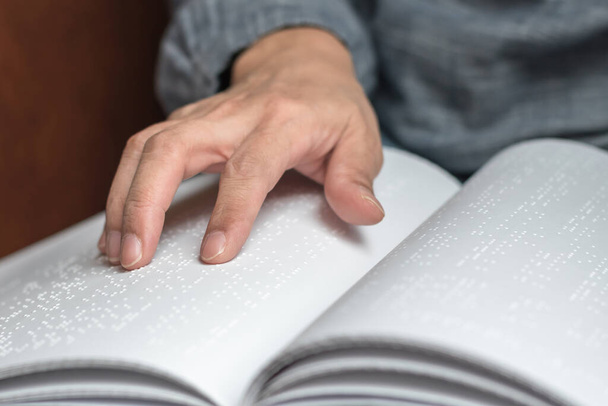 Książka Braille 'a z zaburzeniami wzroku, słabowidząca, osoba niewidoma dotykająca dłoni / palca tekstury papieru czytająca napis - Zdjęcie, obraz