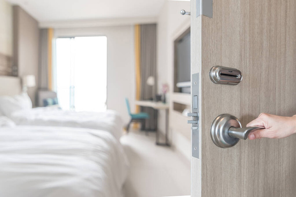 ホテルの部屋のドアは、旅行者のための現代的な快適ベッドの豪華な高品質の生活空間のぼやけた背景と客室のベッドルームのインテリアビューへのロックを解除 - 写真・画像