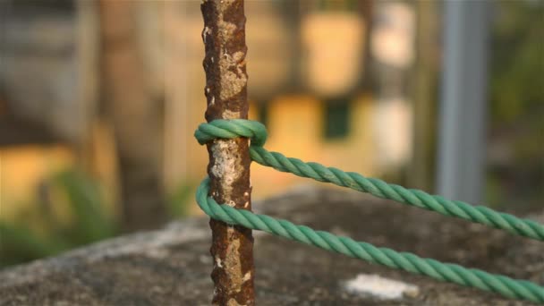 Una cuerda está atada en un nudo alrededor de un poste de la cerca, cuerda atada Hitch Nudos en un poste de hierro oxidado aislado del fondo. - Imágenes, Vídeo