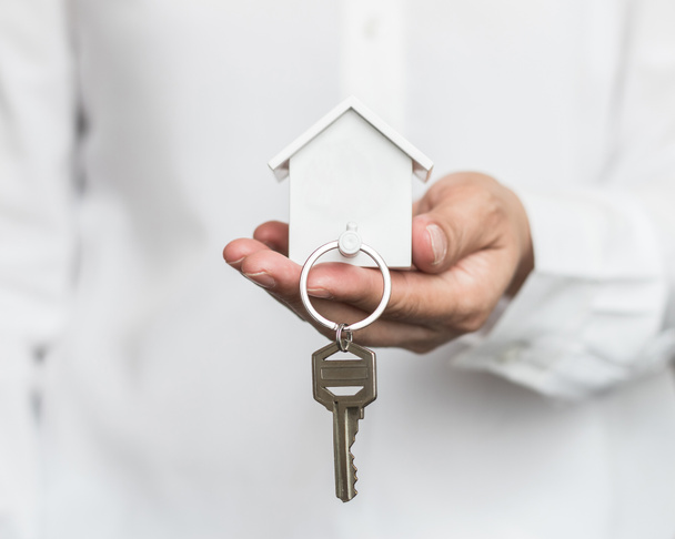 Κλειδί σπιτιού στην προστασία χεριών μεσίτη ασφαλειών σπιτιού ή στο πρόσωπο πωλητή που δίνει στον πελάτη αγοραστή - Φωτογραφία, εικόνα
