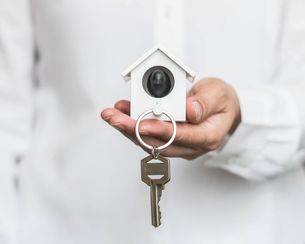 Ключ от дома в страховой брокер руку защиты или в продавца лицо, давая покупателю - Фото, изображение
